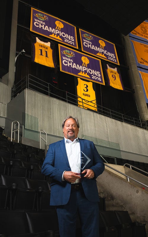 Ron Little poses in front of the Los Angeles Sparks banners inside Crypto.com Arena.